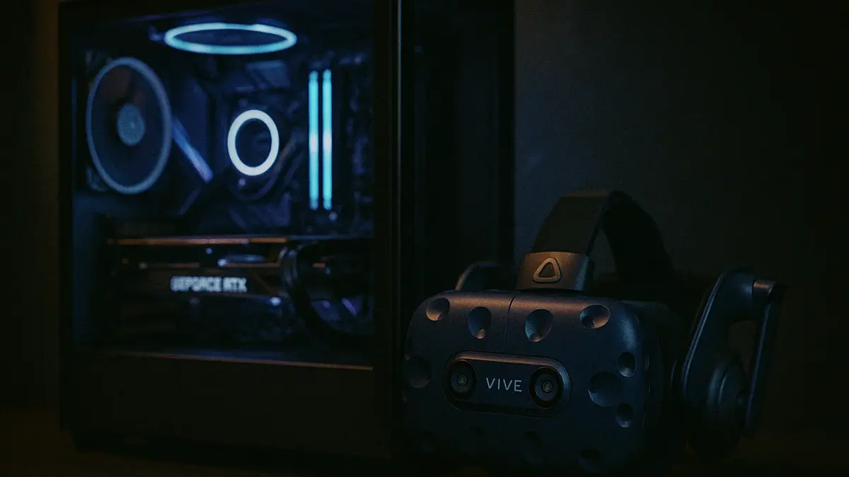 Un PC da gaming performante con componenti illuminati a LED accanto a un visore per la realtà virtuale HTC Vive Pro 2